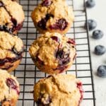 Angled view of blueberry oatmeal muffins cooling on a black wire rack.