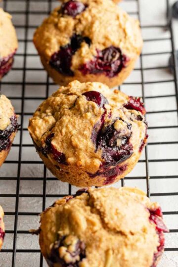 Angled view of blueberry oatmeal muffins cooling on a black wire rack.