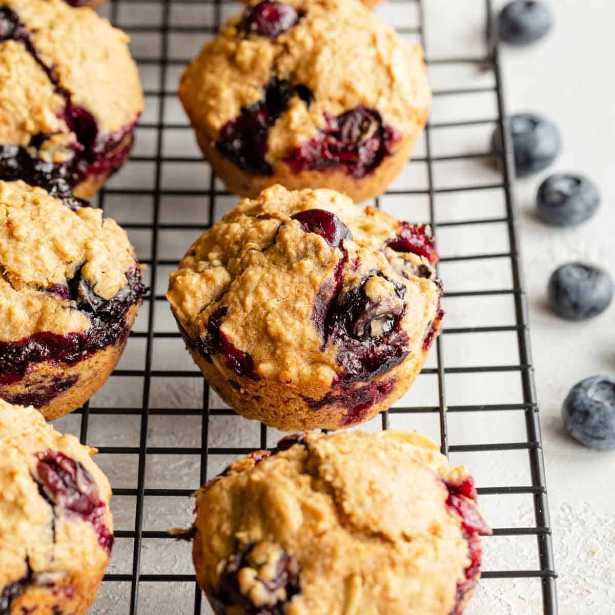 Angled view of blueberry oatmeal muffins cooling on a black wire rack.