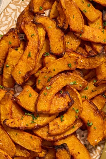 Close up of air fryer pumpkin fries served on a platter with parsley on the side.