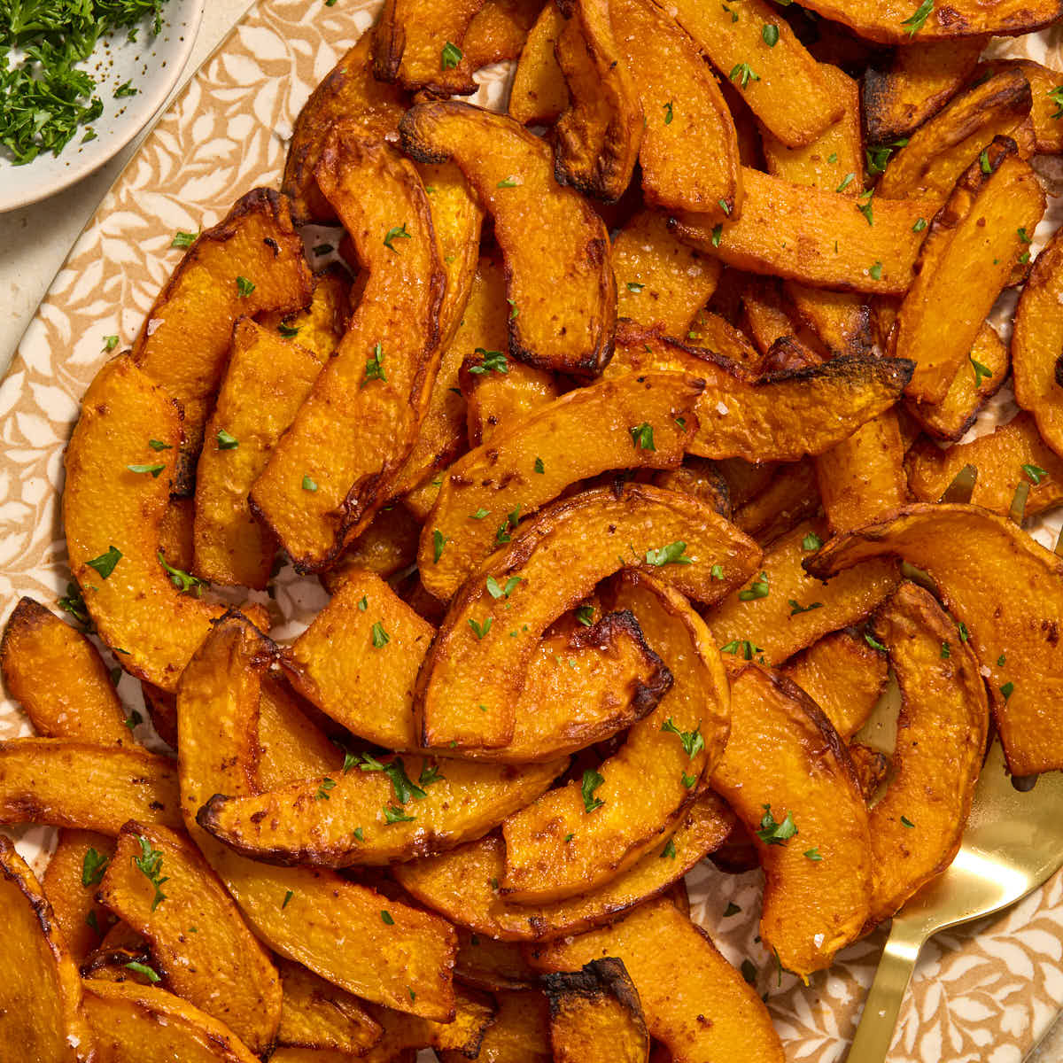 Close up of air fryer pumpkin fries served on a platter with parsley on the side.