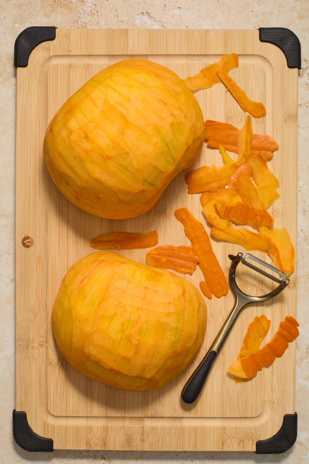 Skin peeled off two pumpkin halves on a wooden board.