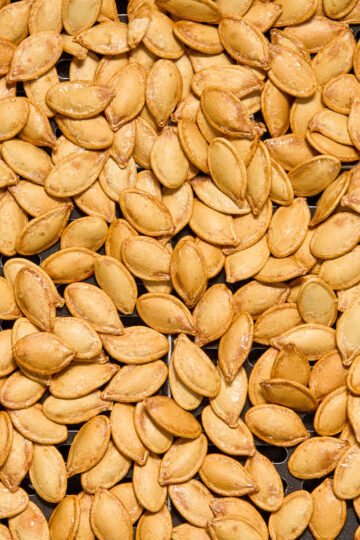 Close up view of air fryer pumpkin seeds in an air fryer basket.