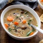 Chicken and wild rice soup in a white bowl with a spoon inserted into it.