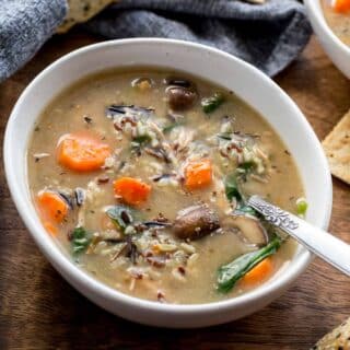 Chicken and wild rice soup in a white bowl with a spoon inserted into it.