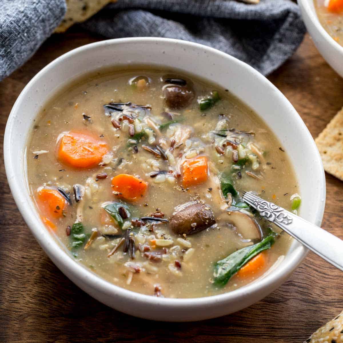 Chicken and wild rice soup in a white bowl with a spoon inserted into it.