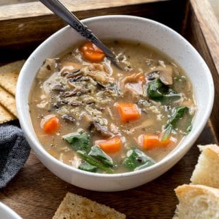 Instant Pot Chicken Wild Rice Soup in a white bowl arranged on a wooden serving tray.