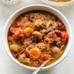Overhead close up of vegetarian chili in a white bowl with a spoon.