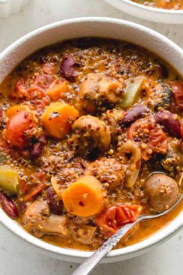 Overhead close up of vegetarian chili in a white bowl with a spoon.