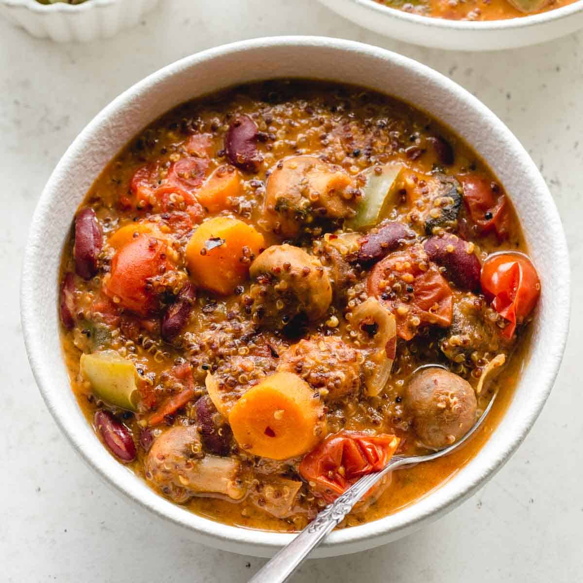 Overhead close up of vegetarian chili in a white bowl with a spoon.