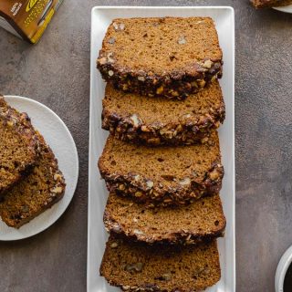 Thick slices of walnut banana bread with molasses arranged on a white plate.