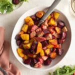 Chopped beets (red, golden and candy cane) air fried and served in a white bowl with a spoon.