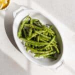 Air fried green beans in a white oval dish.