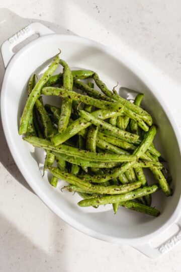 Air fried green beans in a white oval dish.