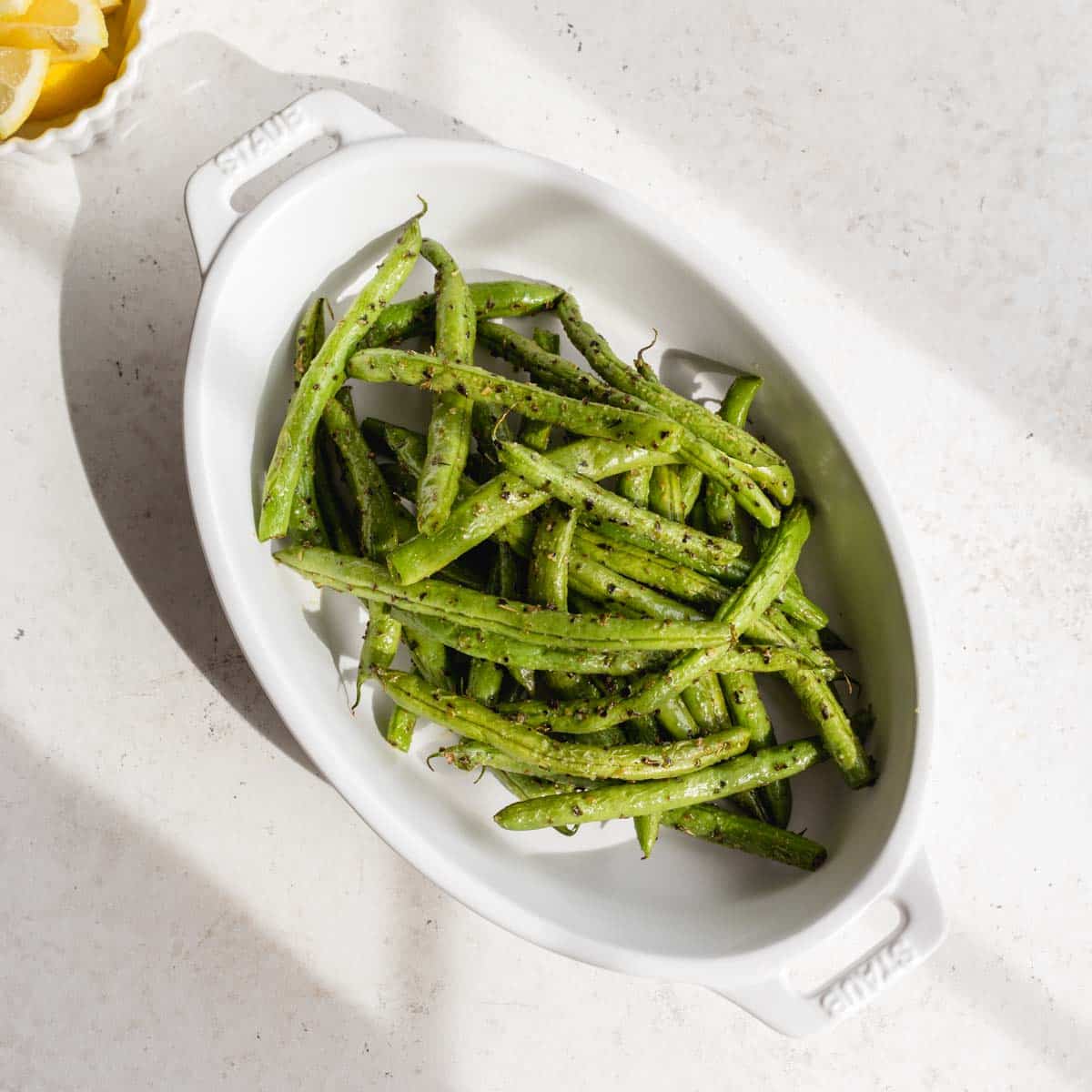 Air fried green beans in a white oval dish.