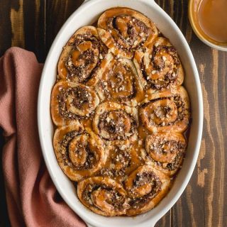 Overhead view of chocolate hazelnut rolls in a white dish on a brown wooden surface.