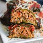 Side view of ground turkey stuffed collard greens cut in half on a plate.