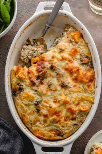 Overhead of ground turkey sweet potato casserole in a white oval dish with some scooped out with a spoon.