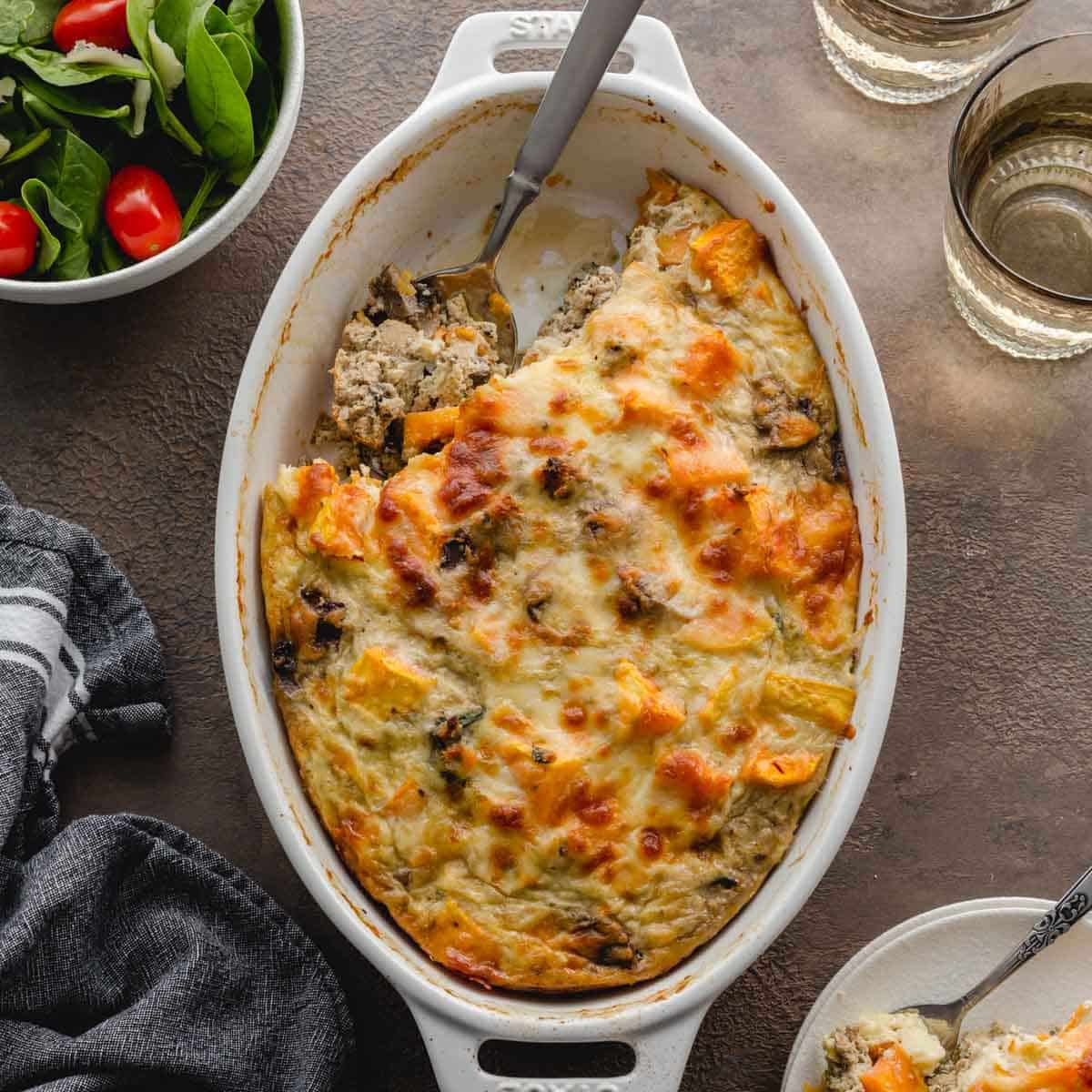 Overhead of ground turkey sweet potato casserole in a white oval dish with some scooped out with a spoon.