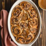 Overhead of Nutella rolls in a white oval dish on a wooden surface.