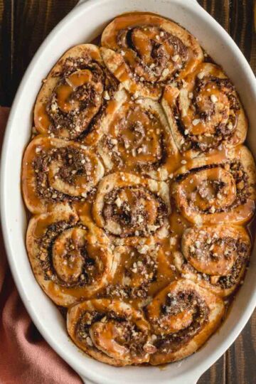 Overhead of Nutella rolls in a white oval dish on a wooden surface.