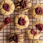 Cranberry thumbprint cookies arranged on a wire rack.