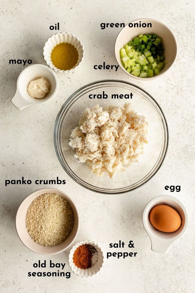 Overhead view of ingredients to make this crab cake recipe, arranged individually and labelled.