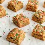 Christmas blondies cut into squares and arranged on a sheet of parchment paper.