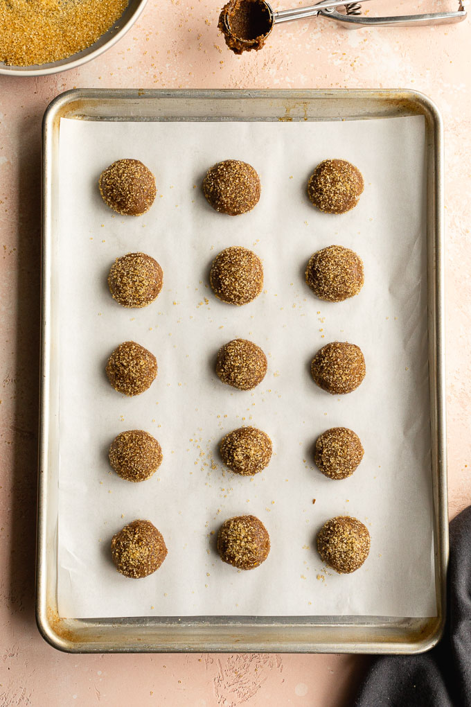 Cookie dough balls rolled in sugar and arranged on a baking sheet.