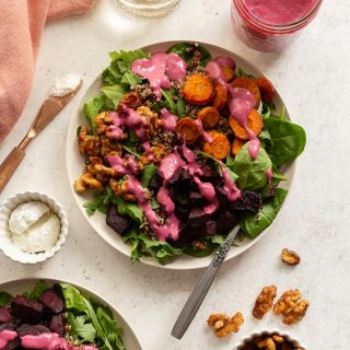 Roasted Beet and Carrot Salad arranged on plates and topped with cranberry salad dressing.
