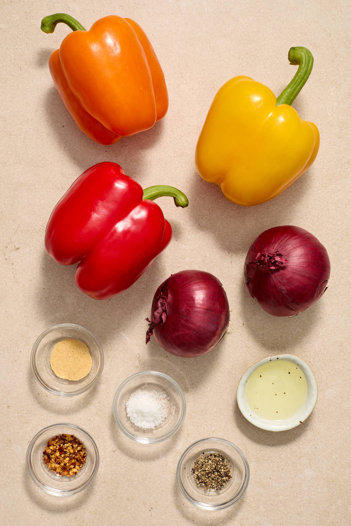 Ingredients to make air fryer peppers and onions arranged individually on a work surface.