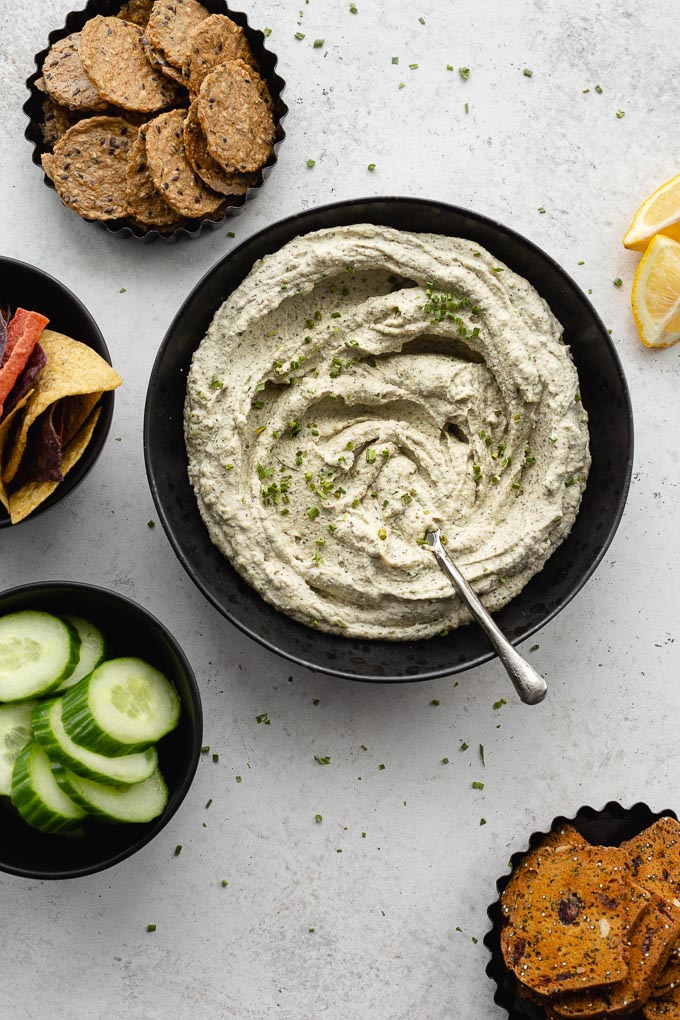 Overhead view of vegan herb dip swirled around in a black bowl with a knife.