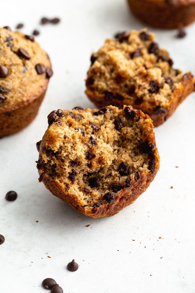 Two muffin halves laying on a white surface showing the chocolate chips inside.