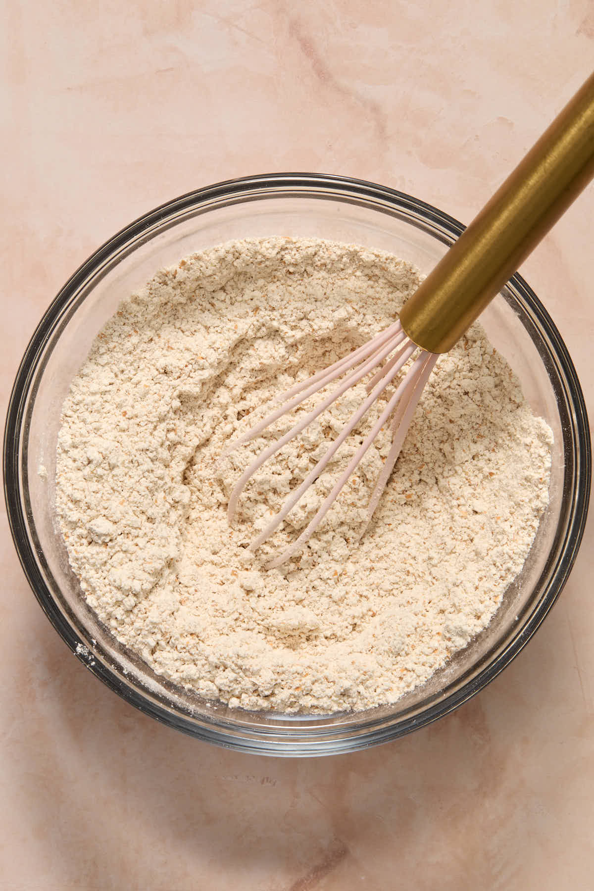 Dry ingredients for muffins whisked together in a smaller glass bowl.