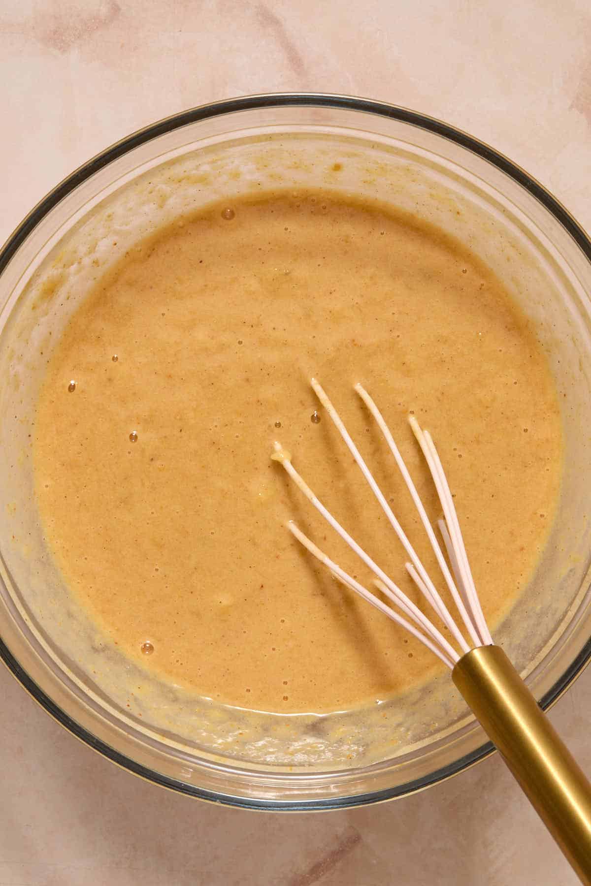 Wet ingredients for muffin batter whisked together in a glass bowl.