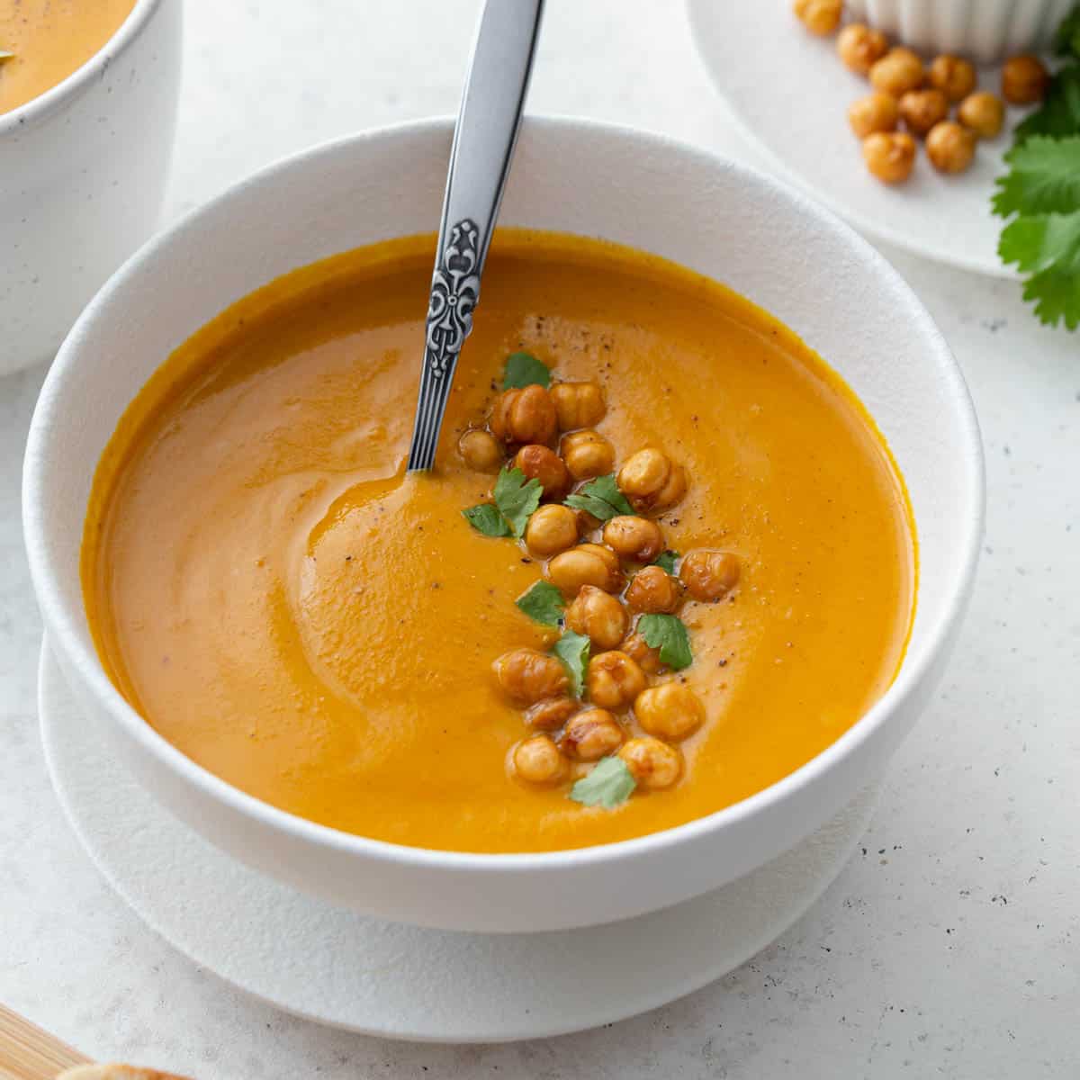 Angled view of sweet potato carrot soup in a white bowl with a spoon.