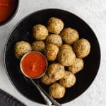 Air fryer chicken meatballs served in a black bowl with forks and marinara sauce on the side.