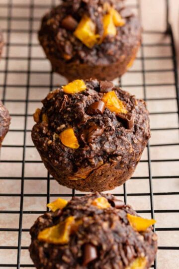 Angled view of chocolate mango muffins on a black wire rack.