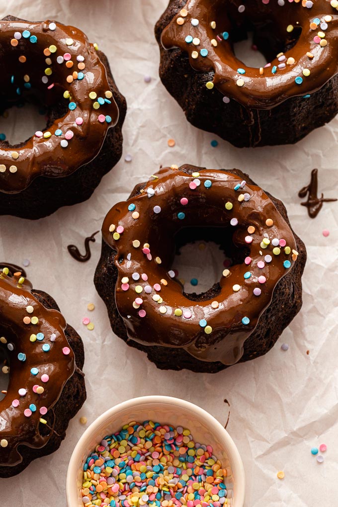 Mini chocolate bundt cakes topped with glaze and sprinkles.