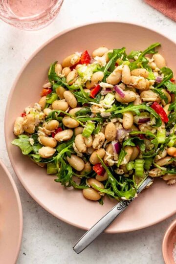 Overhead of tuna white bean salad on a pink plate with a fork.