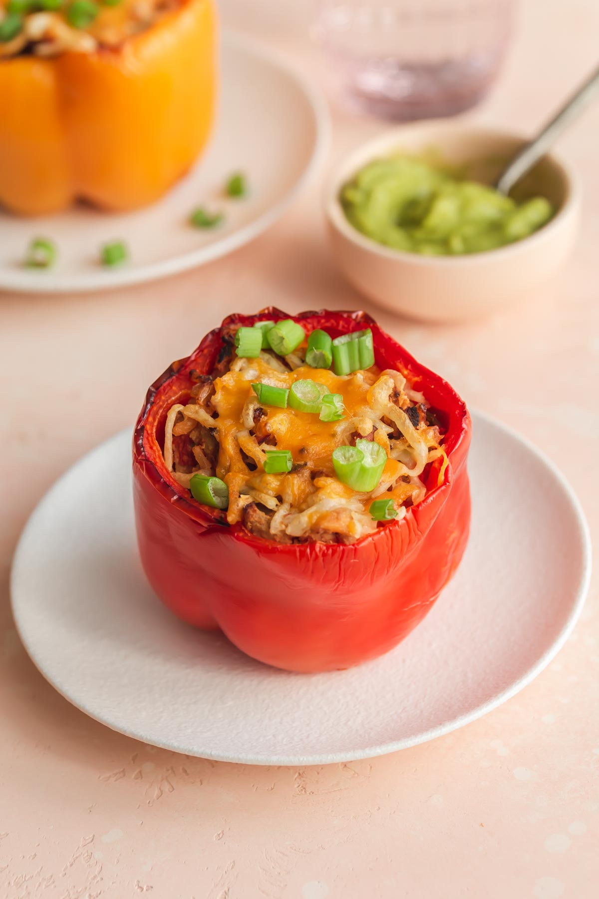 Up close view of a stuffed red bell pepper on a white plate.