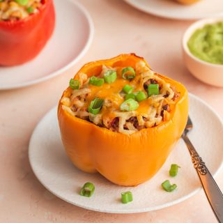 Air fryer stuffed peppers arranged on white plates and garnished with green onions.