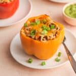 Angled view of an air fryer stuffed pepper on a white plate.