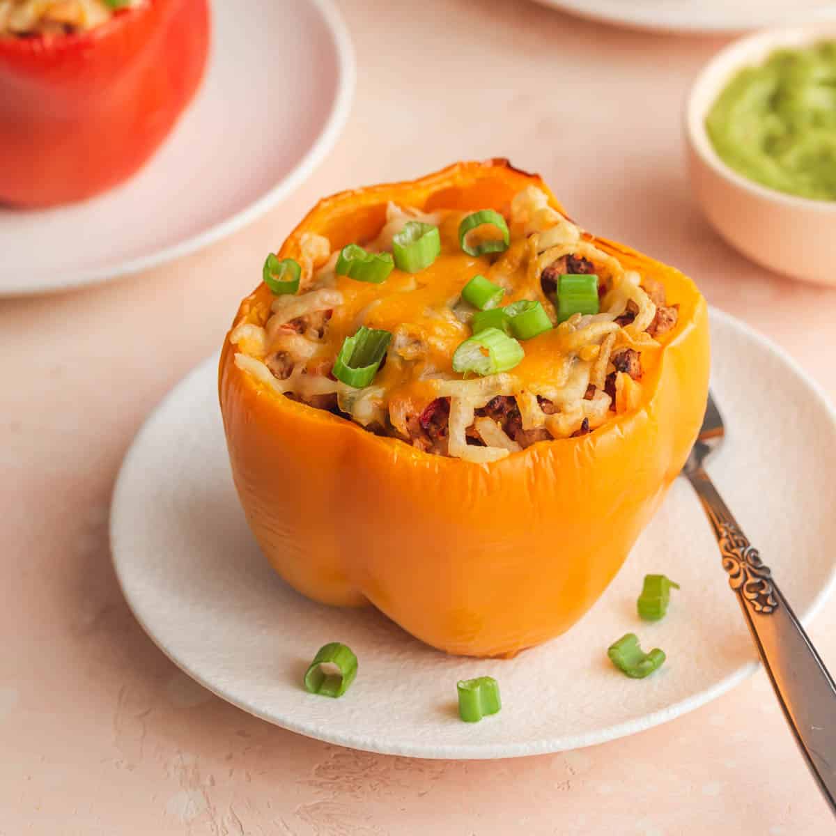 Angled view of an air fryer stuffed pepper on a white plate.