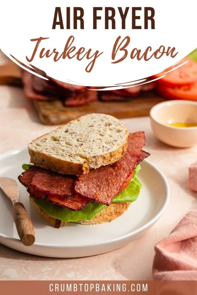 Pinterest image of a turkey bacon, lettuce and tomato sandwich on a white plate.