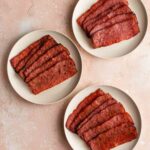 Overhead of three different varieties of air fried turkey bacon on white plates.