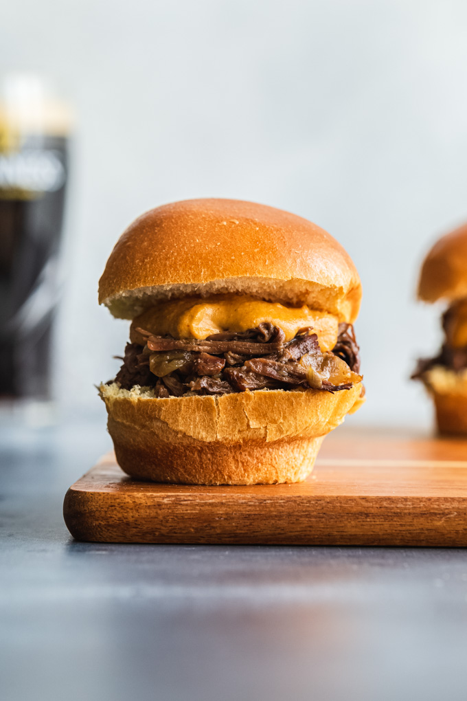 Up close side view of a pulled beef slider on a wooden board.