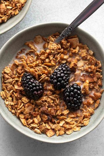 Overhead of a bowl of maple walnut granola with milk and blackberries on top.