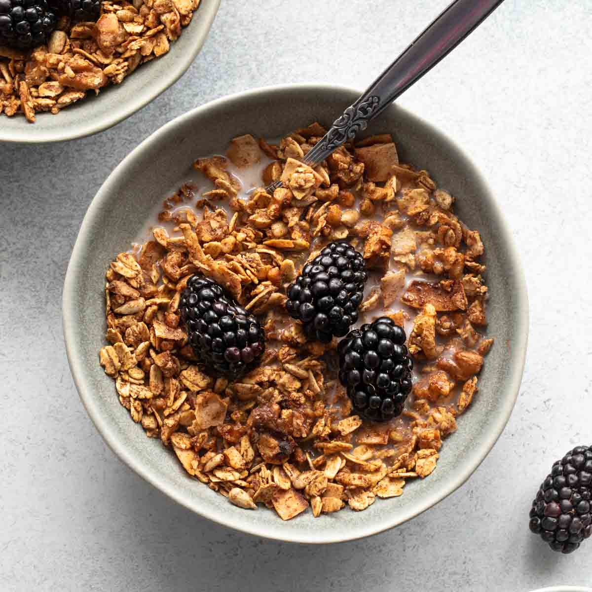 Overhead of a bowl of maple walnut granola with milk and blackberries on top.