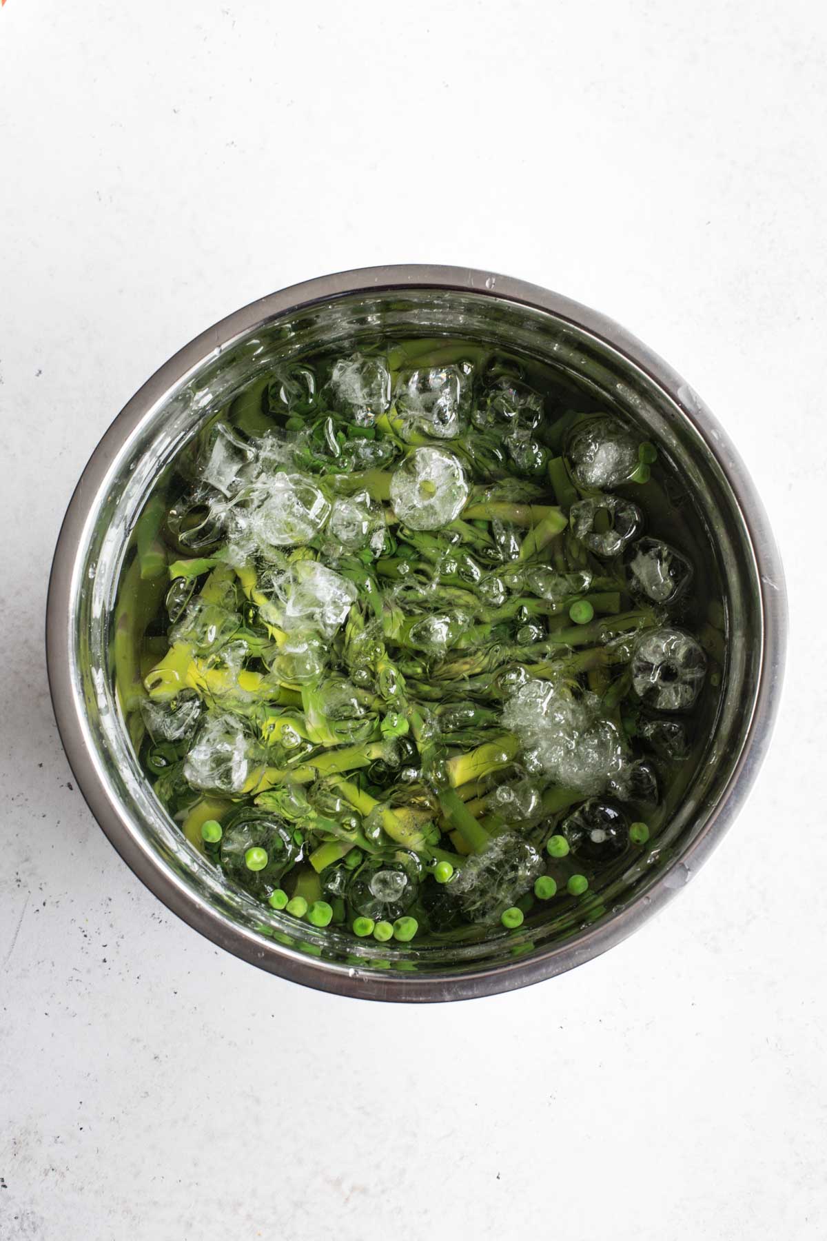 Blanched peas and asparagus in an ice bath.
